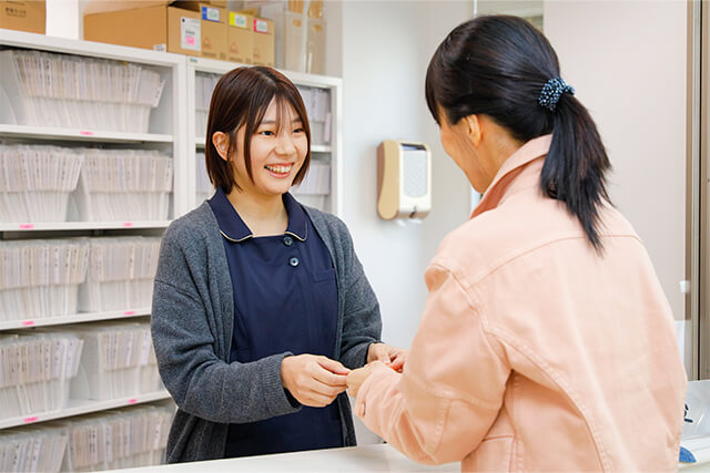 患者に診察券を渡す病院の事務の女性